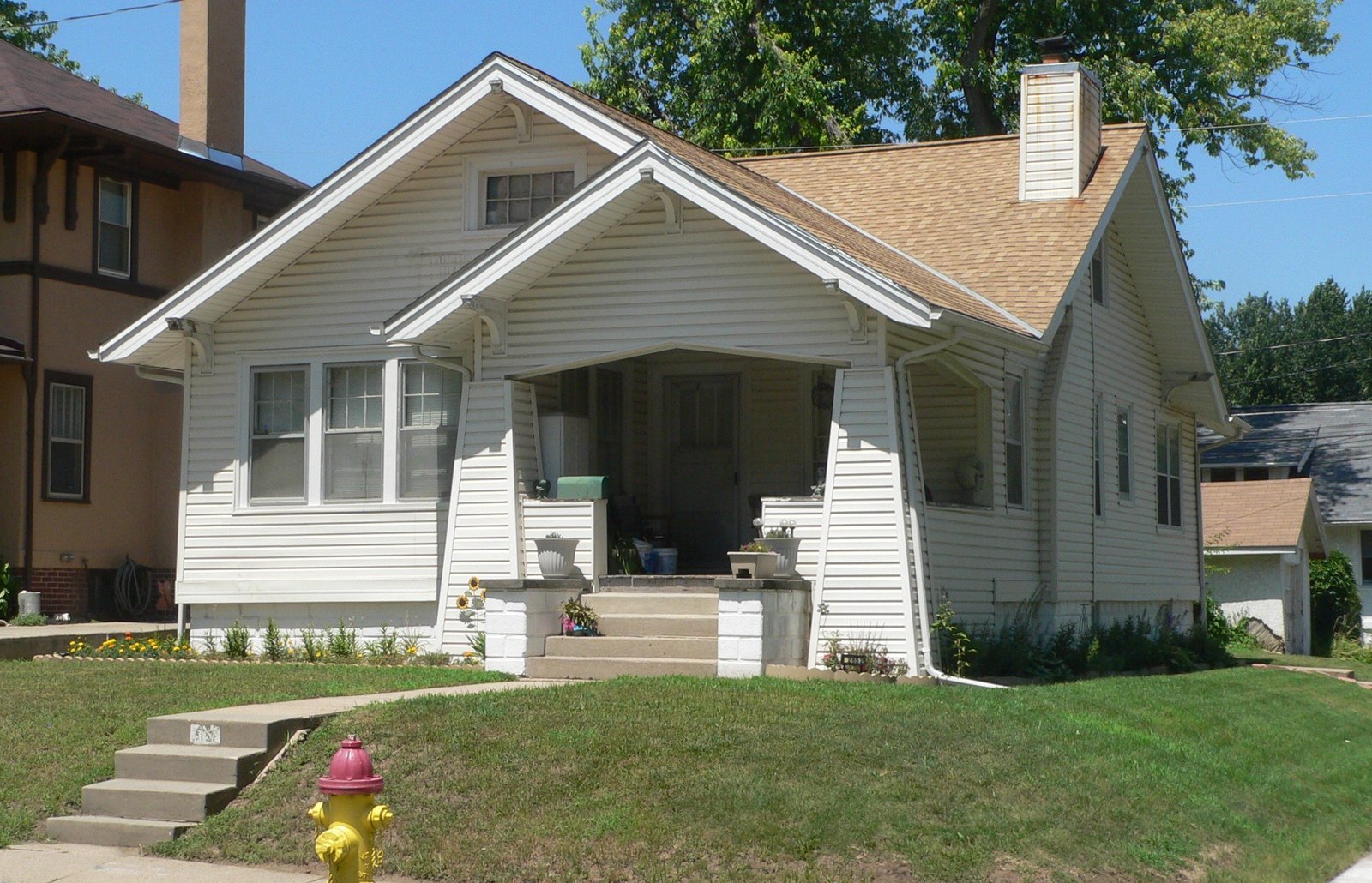 White 1920s bungalow with a front porch and green lawn in Omaha's Minne Lusa neighborhood